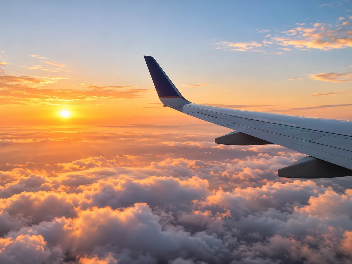Airplane wing above clouds at sunset